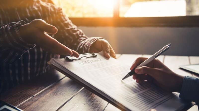 a man handing over a contract with the other person holding a pen ready to sign 