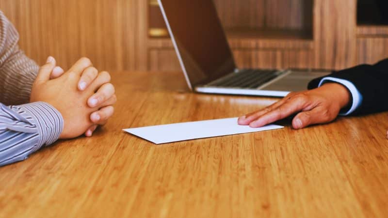 man handing over a letter at a table to say they are redundant