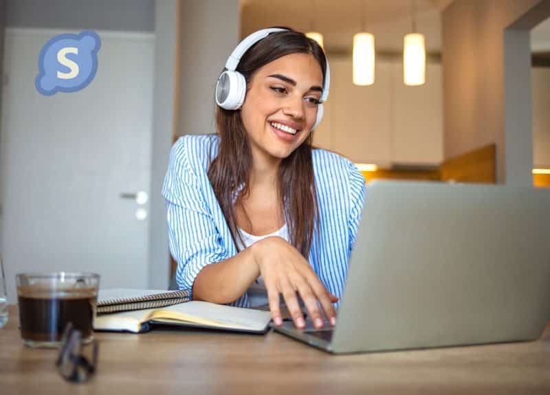 woman with brown hair and headphones on her laptop on a skype call