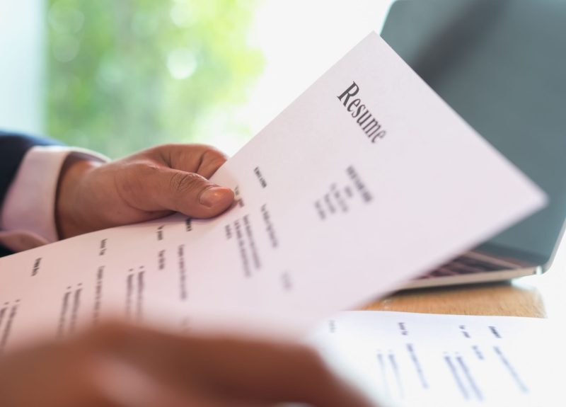 Man holding a resume with him sat at a table
