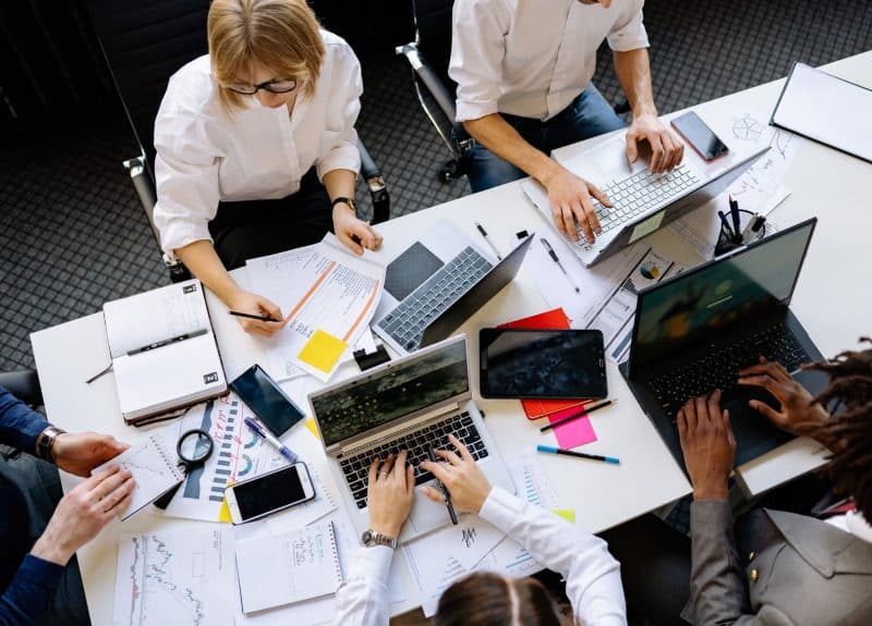 office workers sat round a meeting table working and planning