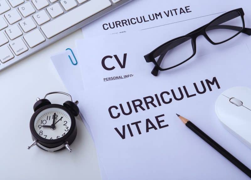 cv on a table with glasses, clock and keyboard