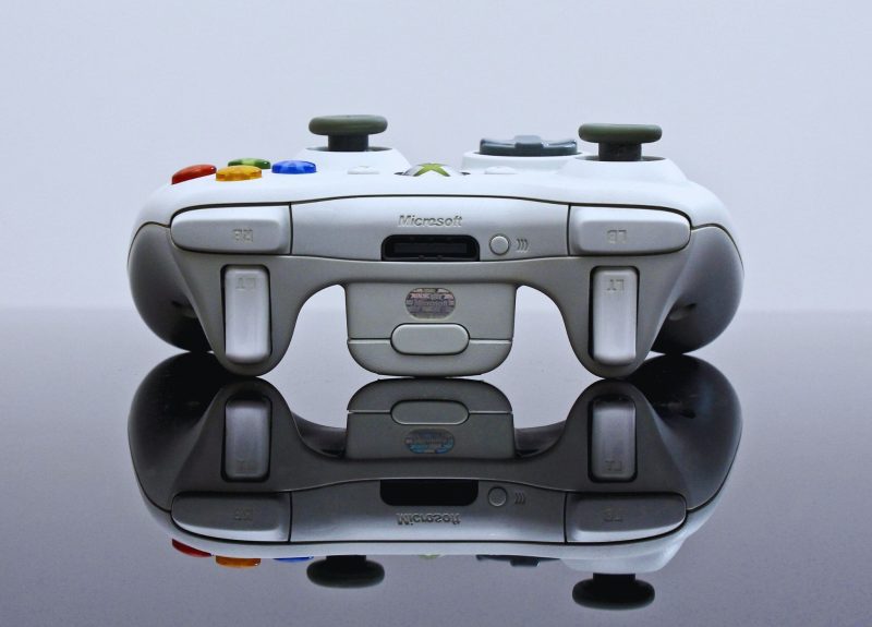 a Microsoft Xbox controller facing upwards on a glass table