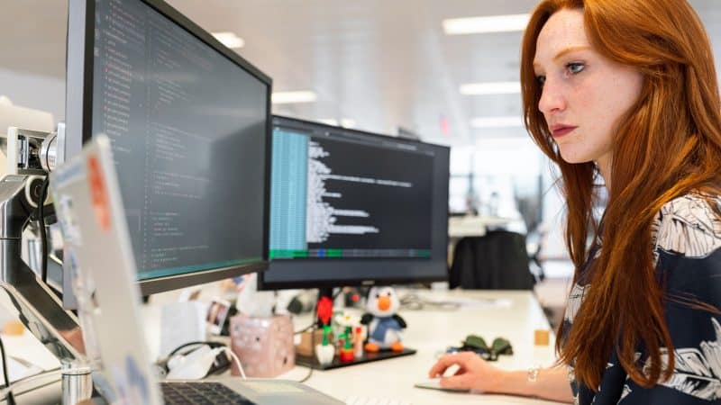 woman working in cloud sat her desk working on 2 monitors 