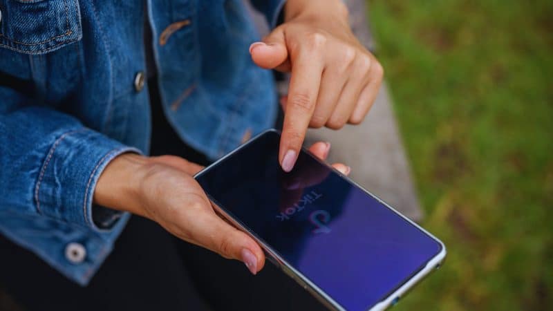 Girl sat down outside logging into tik tok