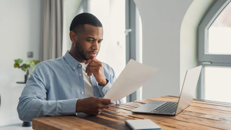 man sat in his home office reading out a printed cv
