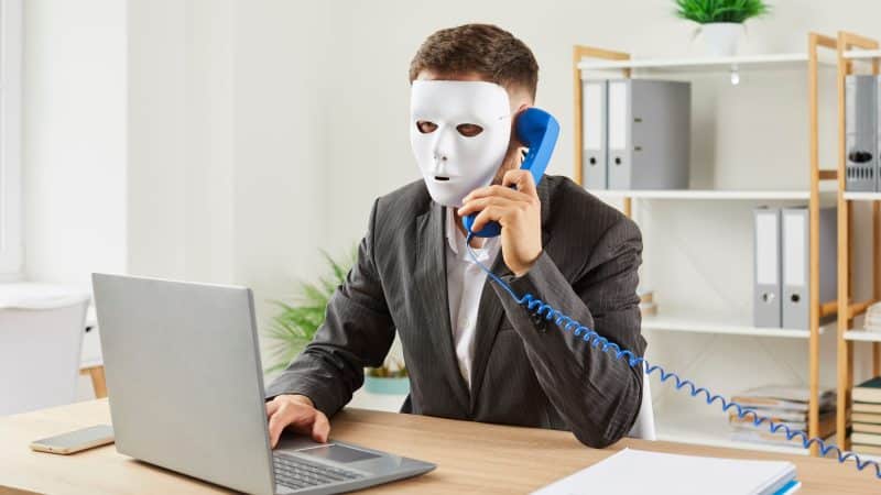 man on the phone with a white mask on to hide his identity