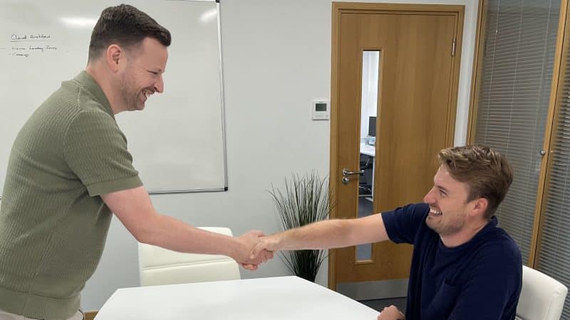 bob and dom hand shaking over the table