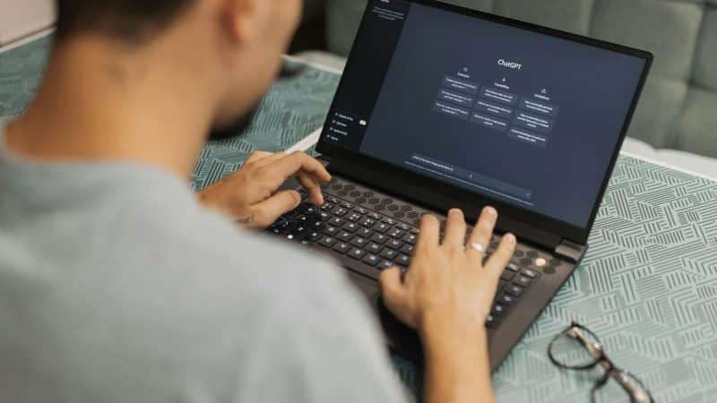 young man using chat gpt on his computer screen sat at a desk 